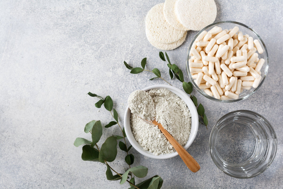 Collagen in a ceramic bowl with spoon and capsules, loofah sponges, and dry eucalyptus branches