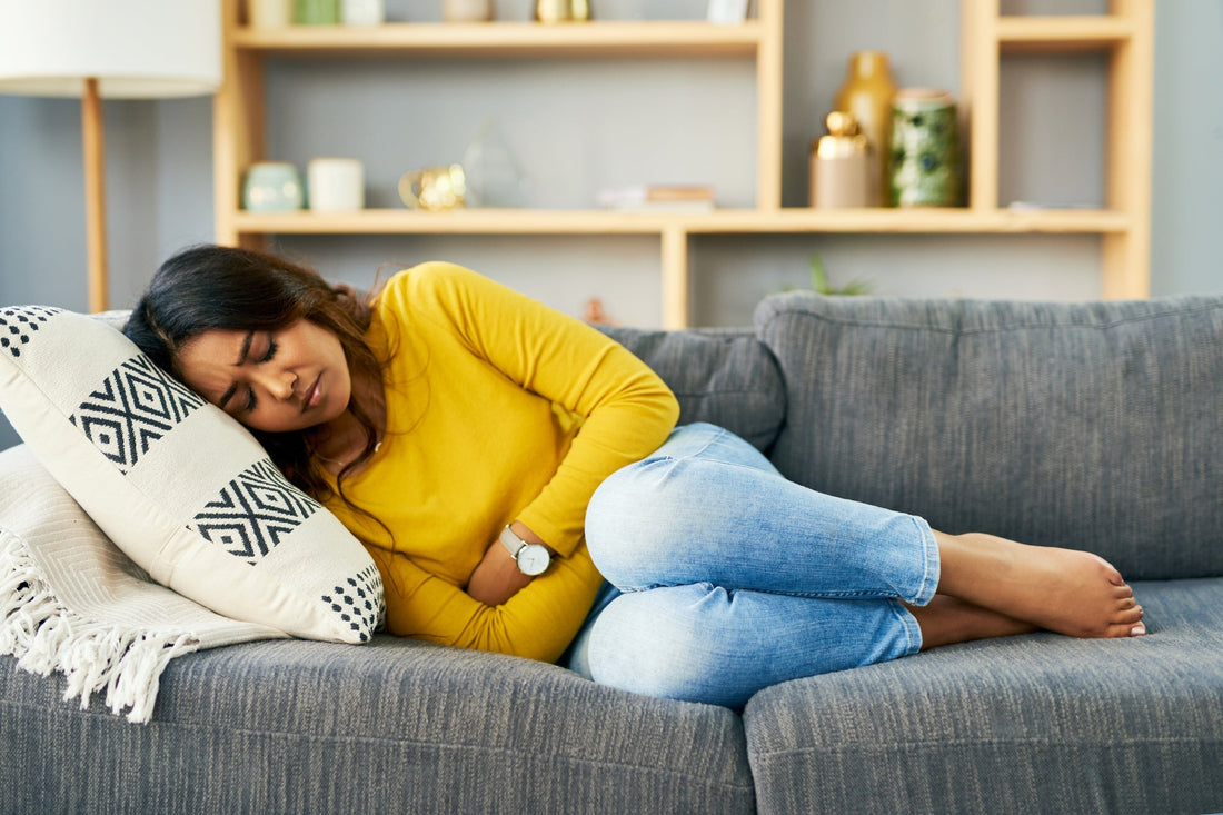 Shot of a young woman experiencing stomach cramps at home.