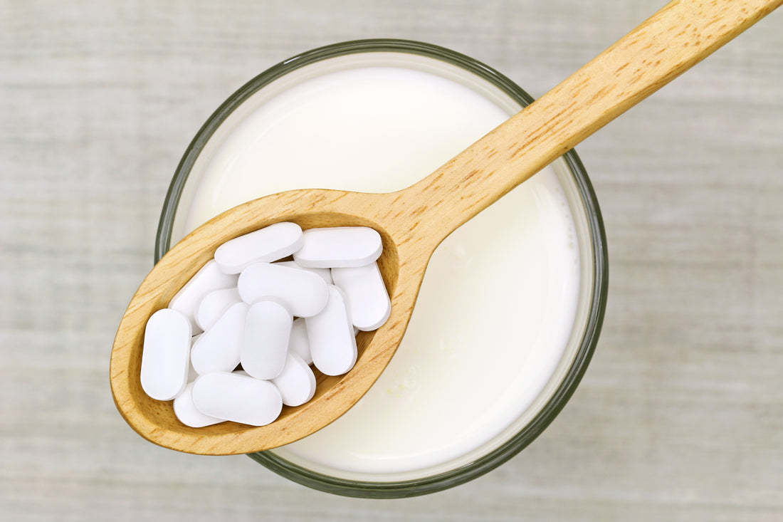 Wooden spoon of Calcium Carbonate tablets above a glass of milk