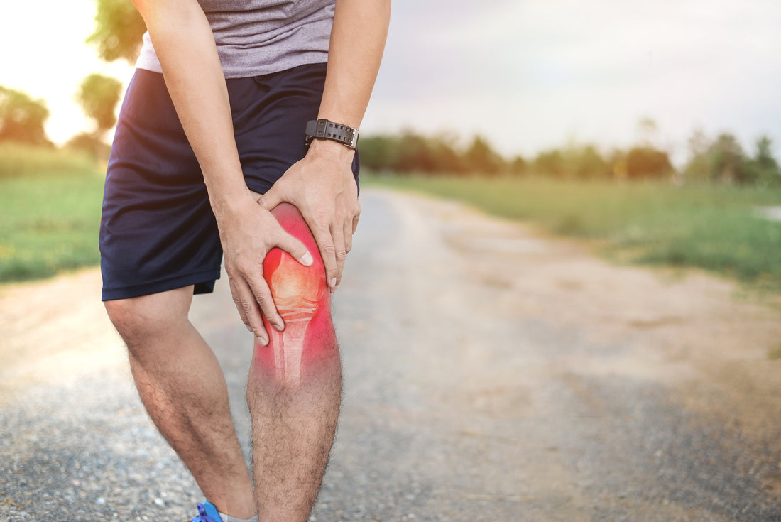 Jogging man holding knee with red colouring showing pain 
