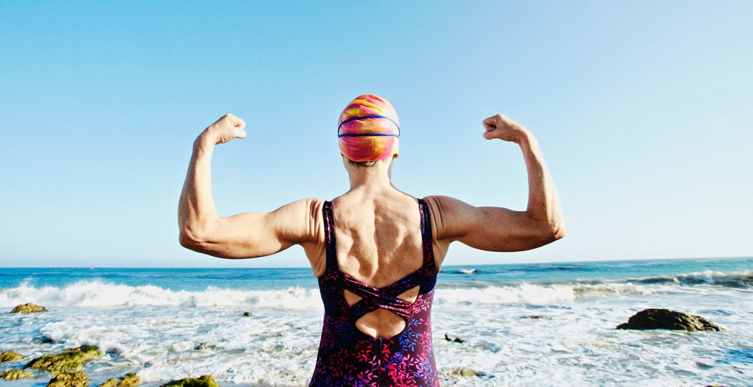 50 year old woman flexing muscles on a rocky beach