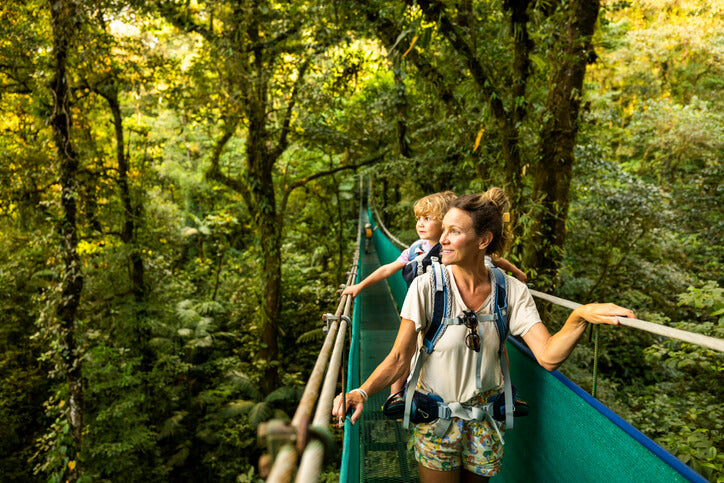 Mother and young son crossing a suspension bridge on a hike